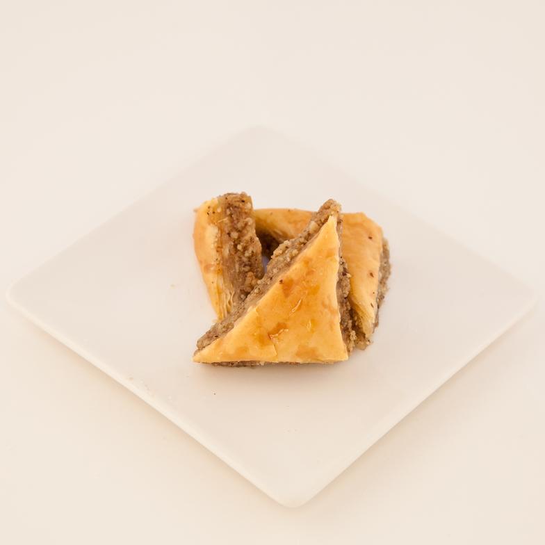 A sweet flaky Greek pastry with a layer of sweetened walnuts and a hint of almond flavoring, in lined paper cups ready to serve.